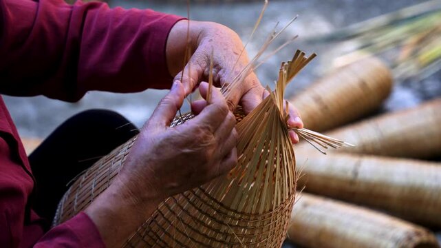 View of Vietnamese craftsman making the traditional bamboo fish trap or weave at the old traditional house in Thu sy trade village, Hung Yen, Vietnam