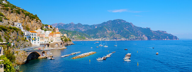 Fototapeta premium Amalfi, Italy. Panoramic view of Atrani and the Amalfi Coast on a sunny summer day. In front of the coast some boats moored. Banner header image.