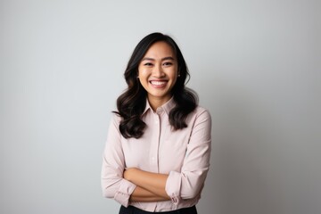 Portrait of a smiling young asian businesswoman standing against grey background
