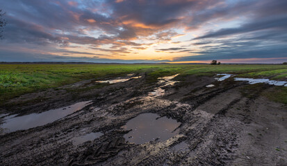 A field with puddles of water and a beautiful sunset in the background
