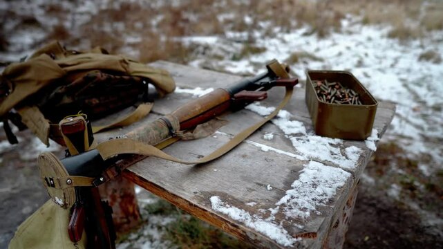 A box of machine gun ammo. There are a lot of machine gun ammo on the table. A grenade launcher is lying next to a box of ammo on a table in a field on a military training ground