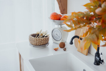 Seasonal kitchen arrangement with autumn decor, fruits, and utensils on a countertop