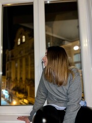 Woman looking out of a window at night in Budapest