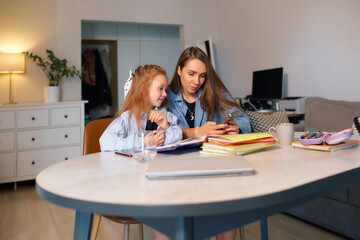 Young mother helps her daughter with her school homework