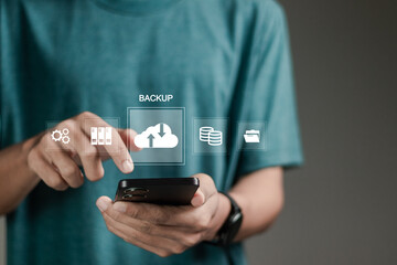 Backup concept, Online digital data storage and connection service. Person using smartphone with backup icons on virtual screen for data backup management.