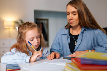 Fototapeta premium Schoolgirl sits with her mother and learns a new language