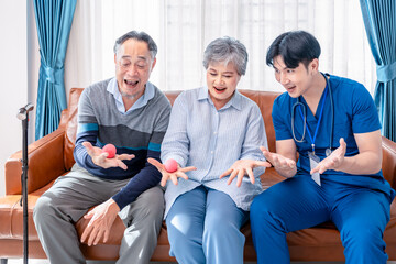 young male assistant in uniform advice asian senior couple exercise hands with a ball,home health care nurse visit asian senior family at home,concept elderly health care,homecare,home health nursing