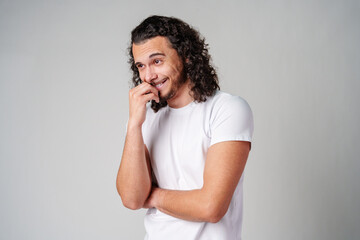A young man stands thoughtfully against a plain background, expressing contemplation