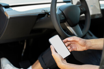 Man sitting in driver seat holding smartphone with white screen