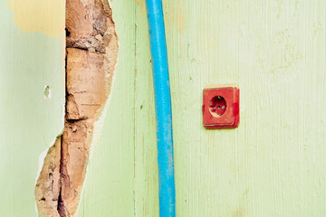 Old dirty electrical socket,electric cable on cracked wall before renovation