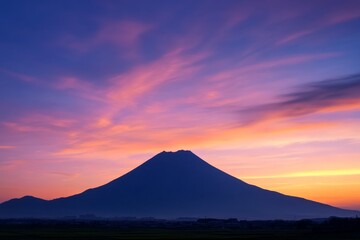 Fototapeta premium A stunning silhouette of a mountain against a colorful sky during sunset, exuding tranquility and magnificence, with hues of pink, purple, and orange blending together.