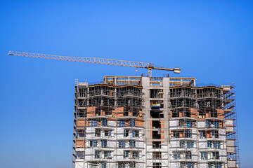 Under construction building against the sky and tower cranes