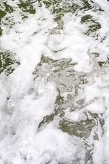 Water of little stream with foam on entire surface. Environmental pollution