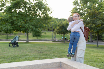 Fototapeta premium A woman is holding a child in her arms in a park