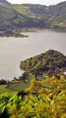 The photo shows a huge green lake amidst green hillsides, with a blue sky in the background. The sun is charmingly illuminating the hills. The water shimmers with shades of green and blue. © Wiktor