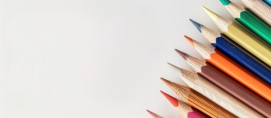 Fototapeta premium Colorful pencils viewed from above on a white backdrop with space for text or design Ideal for school office or art themed backgrounds. with copyspace image