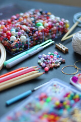 Colorful beads, coloring pencils, glitter, needles, string, hoop, tape and scissors on dark...