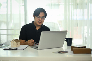 Fototapeta premium Handsome asian man working with interior design project at creative office