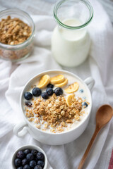 Breakfast bowl with greek yogurt, crunchy granola, blueberries and banana slices. Selective focus