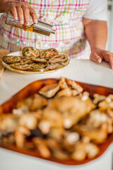 Elderly person drizzling olive oil on marinated tomatoes
