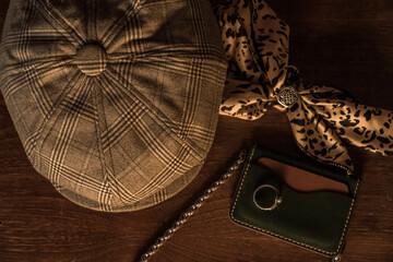 Classic newsboy cap or eight panel hat made of herringbone wool fabric lying on a dark brown wooden...