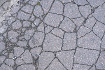 old cracked asphalt close-up, old cracked symmetrical pavement as a background, cracks on macro asphalt