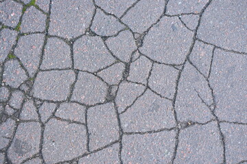 old cracked asphalt close-up, old cracked symmetrical pavement as a background, cracks on macro asphalt