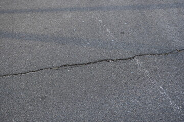 Cracks on grey asphalt close-up, old cracked asphalt close-up, old road surface bitumen  