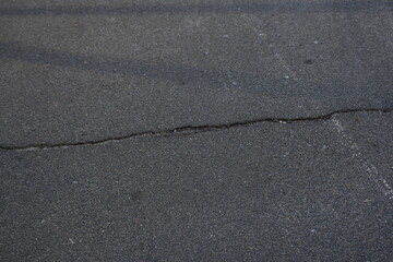 Cracks on grey asphalt close-up, old cracked asphalt close-up, old road surface bitumen  