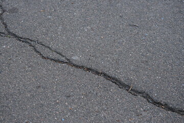 Cracks on grey asphalt close-up, old cracked asphalt close-up, old road surface bitumen  