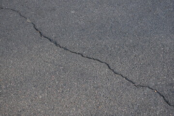 Cracks on grey asphalt close-up, old cracked asphalt close-up, old road surface bitumen  