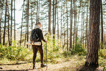 Young caucasian man hiking or trekking through the forest 