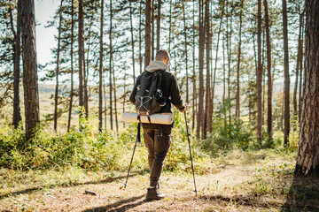 Young caucasian man hiking or trekking through the forest 