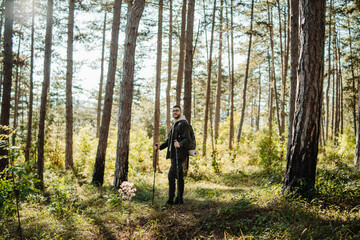 Fototapeta premium Young caucasian man hiking or trekking through the forest 