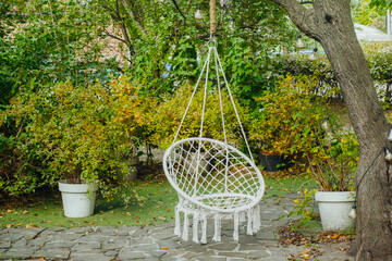 A cozy hanging chair in a lush garden surrounded by greenery