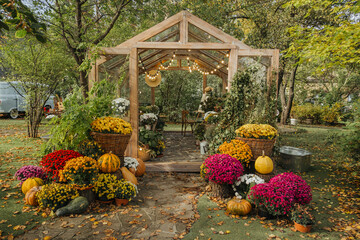 Charming garden greenhouse adorned with autumn flowers and pumpkins