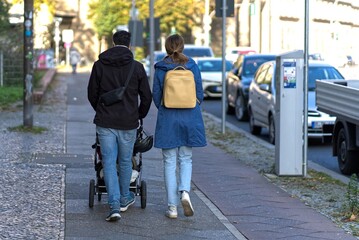Parents with strollers on the sidewalk.