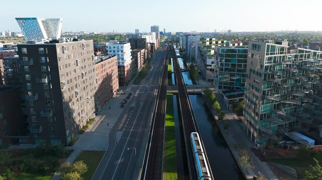 Aerial - train drive on straight railroad through residential area, Copenhagen