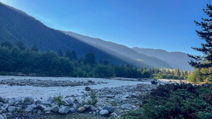 A serene mountain river landscape at dawn highlights the beauty and tranquility of nature, perfect...