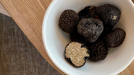 A bowl of fresh black truffles on a wooden table symbolizes gourmet cuisine and luxury in European culinary traditions