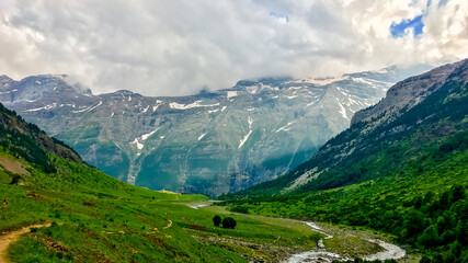Fototapeta premium Breathtaking panoramic view of lush green valley and snow-capped mountains, symbolizing adventure and tranquility, ideal for Earth Day