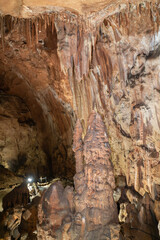 A man is standing in a cave with a large rock formation in front of him