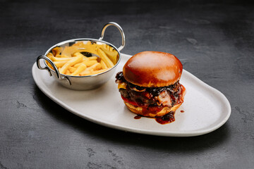 Gourmet BBQ bacon cheeseburger with crispy fries, perfect for indulgent fast food cravings