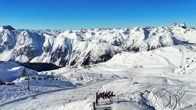 Ischgl, Austria: Aerial view of famous bustling ski resort in Tyrolean Alps. Snow-covered slopes with ski runs, sunny day with clear blue sky - landscape panorama of Europe from above
