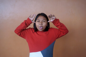 Asian Little Girl Making Funny Face And Showing Tongue. Kid Girl Teasing And Laughing