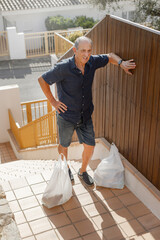 Tired Senior man resting after climbing up stairs with shopping bags. Elderly man suffering...