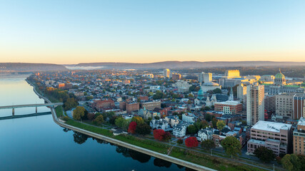 Aerial view of downtown Harrisburg, Pennsylvania, at sunrise, showcasing the city’s historic buildings, streets, and the Susquehanna River, with the landscape bathed in soft morning light.