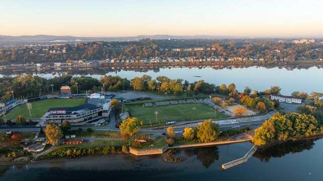 Aerial view of FNB Field in Harrisburg, Pennsylvania, located on an island, with the Susquehanna River and city bridges visible in the background during early morning light.
