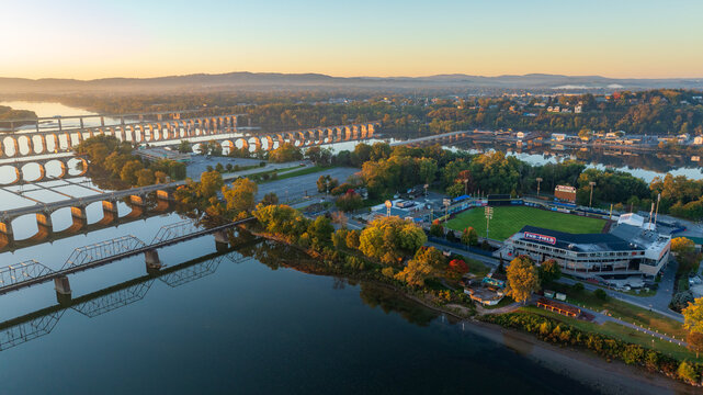 Aerial view of FNB Field in Harrisburg, Pennsylvania, located on an island, with the Susquehanna River and city bridges visible in the background during early morning light.
