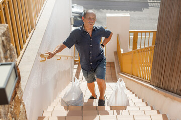 Elderly caucasian man holds his back with painful face because carrying heavy groceries, painful...